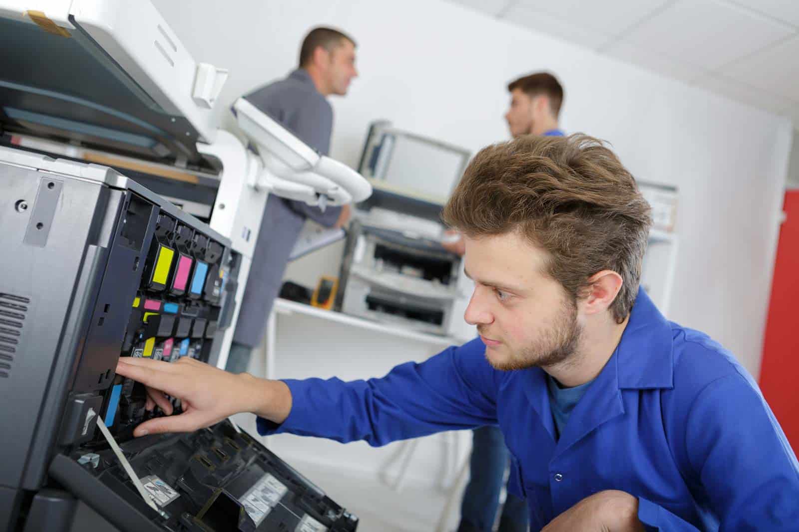 Young male technician working on photocopier